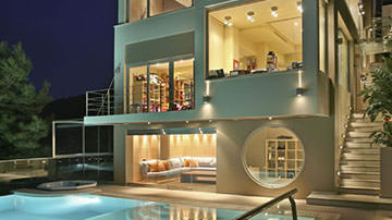 Sleek glazed exterior and illuminated pool area of villa in Voula